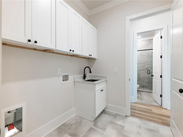 clothes washing area featuring light hardwood / wood-style floors, cabinets, sink, washer hookup, and crown molding