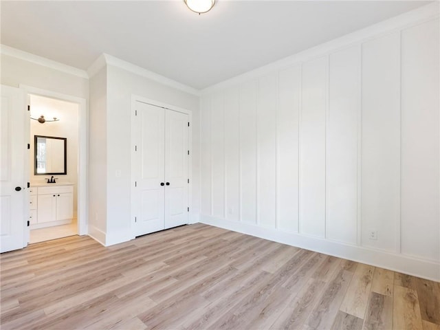 unfurnished bedroom with ensuite bathroom, light hardwood / wood-style flooring, ornamental molding, and sink