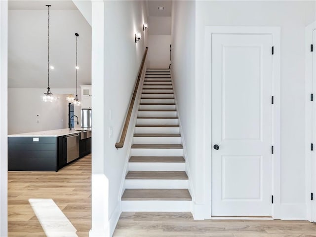 stairway with wood-type flooring, sink, and an inviting chandelier