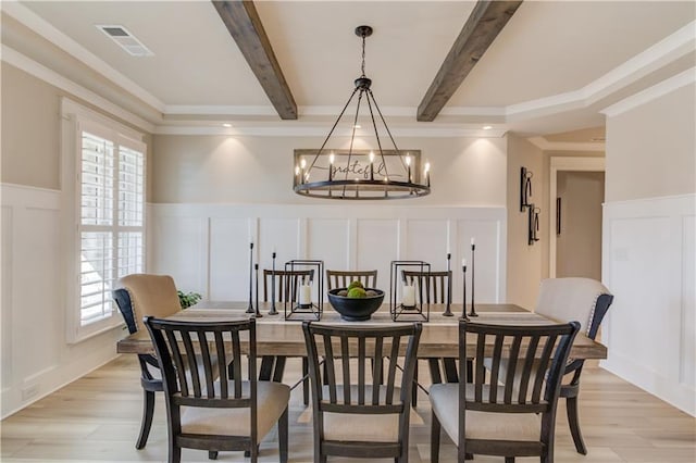 dining area featuring light wood-type flooring, beam ceiling, visible vents, and a decorative wall