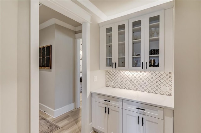 bar featuring light wood-style floors, backsplash, and baseboards