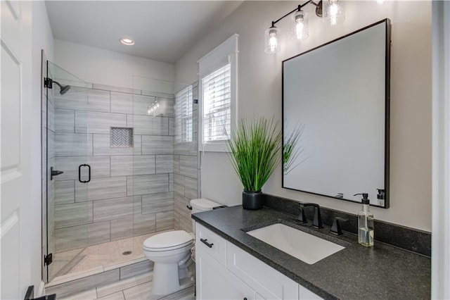 bathroom featuring toilet, a stall shower, and vanity