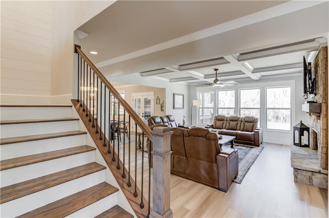 living room with coffered ceiling, a fireplace, stairway, and light wood finished floors