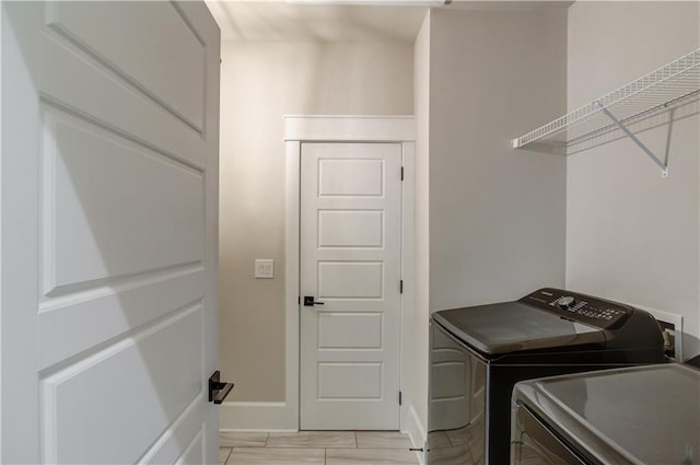 laundry area featuring laundry area, washing machine and dryer, and baseboards