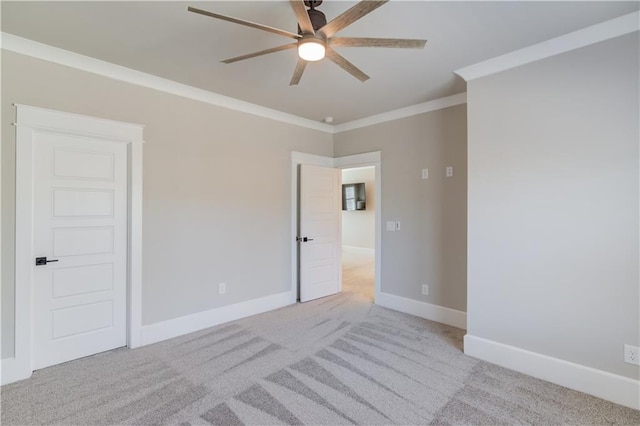 unfurnished room with light carpet, ornamental molding, a ceiling fan, and baseboards