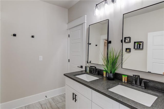 full bath with double vanity, baseboards, and a sink