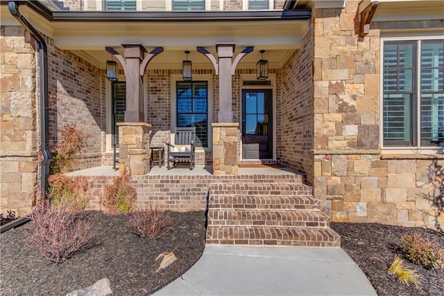 doorway to property with stone siding, a porch, and brick siding