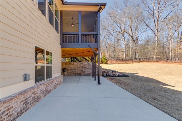 view of patio featuring a sunroom, fence, and a ceiling fan