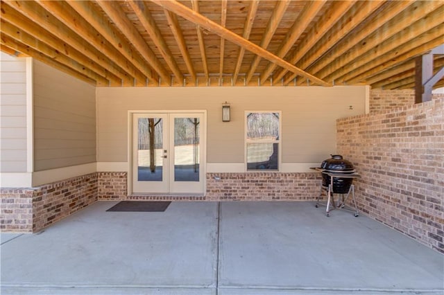 view of exterior entry featuring a patio area, french doors, and brick siding