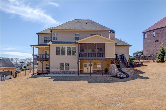 rear view of property featuring stairs, a patio area, fence, and a sunroom