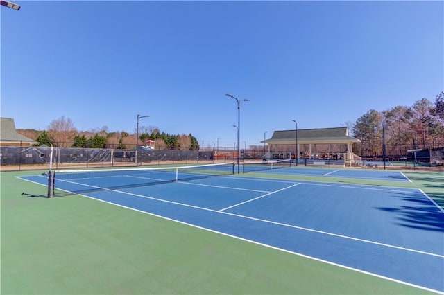 view of tennis court with community basketball court and fence