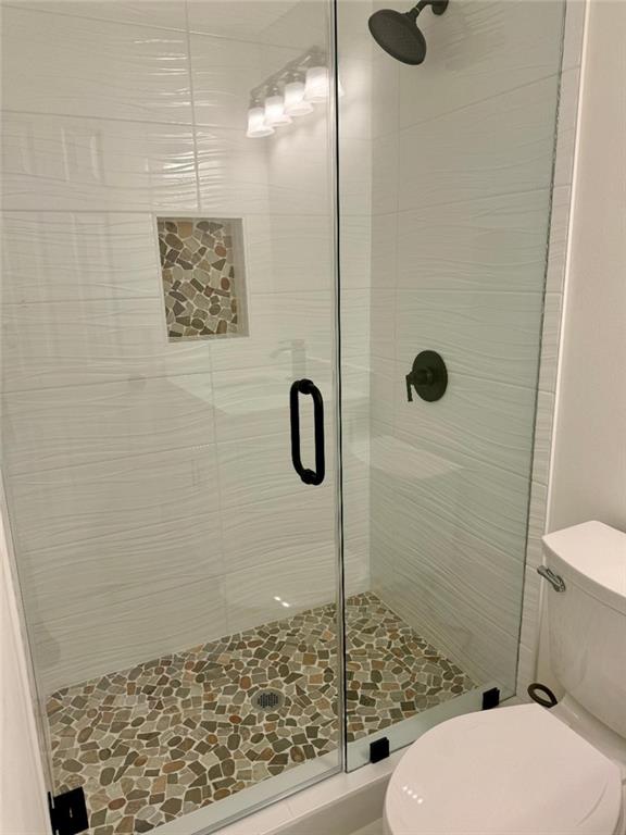 bathroom with a shower with door and toilet