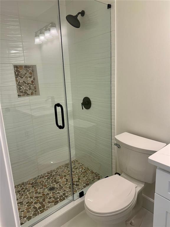 bathroom featuring toilet, an enclosed shower, and vanity