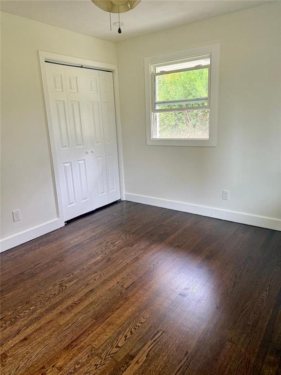 unfurnished bedroom with dark wood-type flooring and a closet