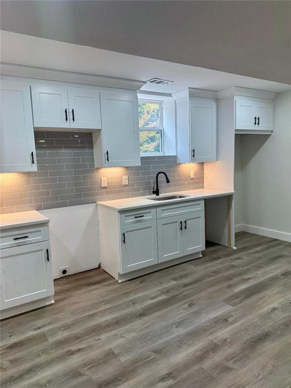 kitchen featuring white cabinetry, decorative backsplash, light hardwood / wood-style flooring, and sink