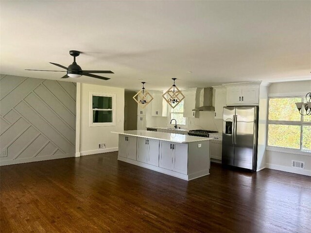 kitchen featuring appliances with stainless steel finishes, plenty of natural light, wall chimney range hood, and pendant lighting