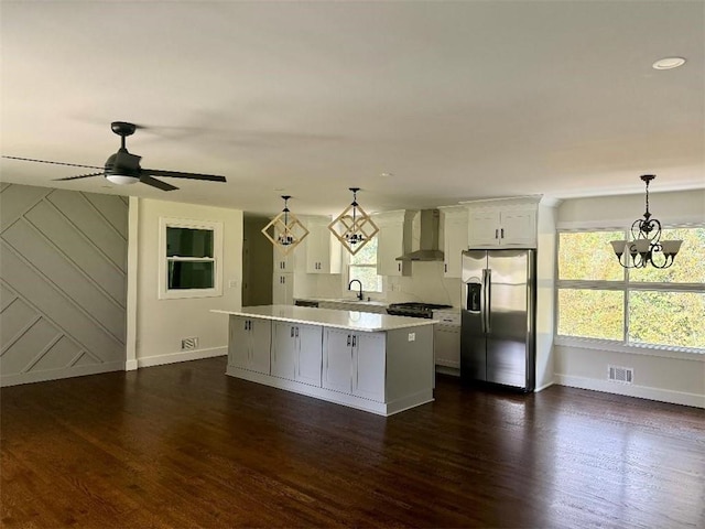 kitchen featuring white cabinets, stainless steel appliances, dark wood-type flooring, wall chimney exhaust hood, and decorative light fixtures