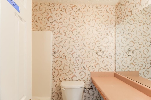 bathroom featuring wallpapered walls and toilet