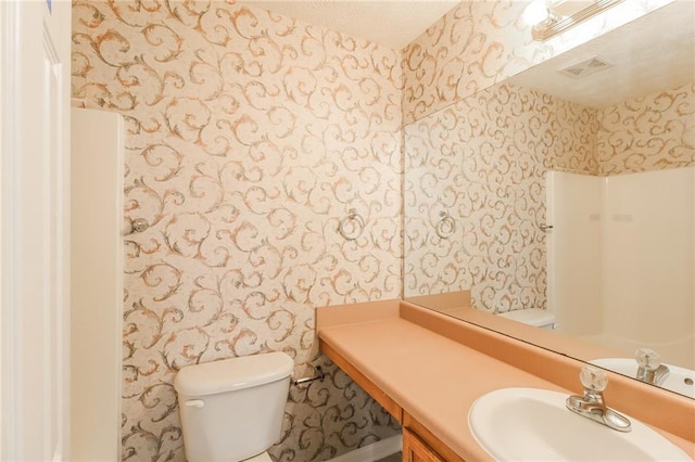 bathroom featuring visible vents, toilet, wallpapered walls, and vanity