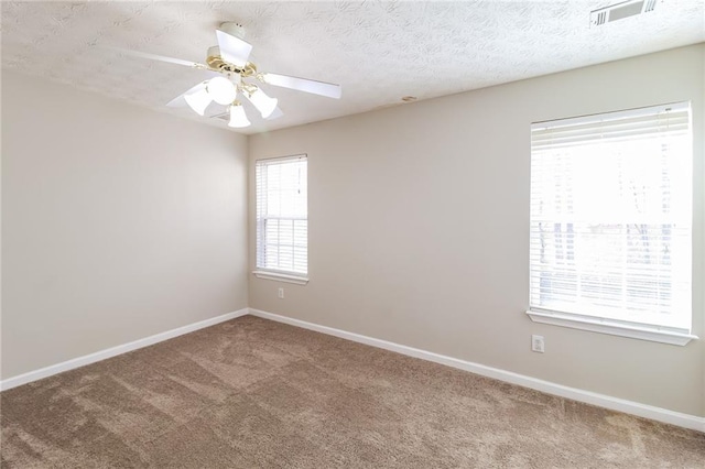 carpeted spare room with visible vents, baseboards, a textured ceiling, and a ceiling fan