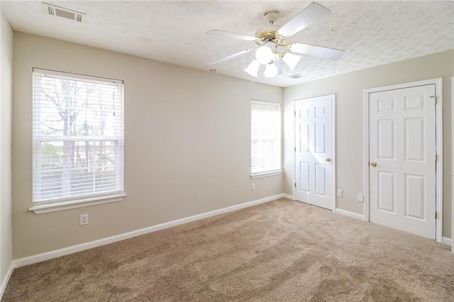 unfurnished bedroom with visible vents, baseboards, a textured ceiling, and carpet flooring