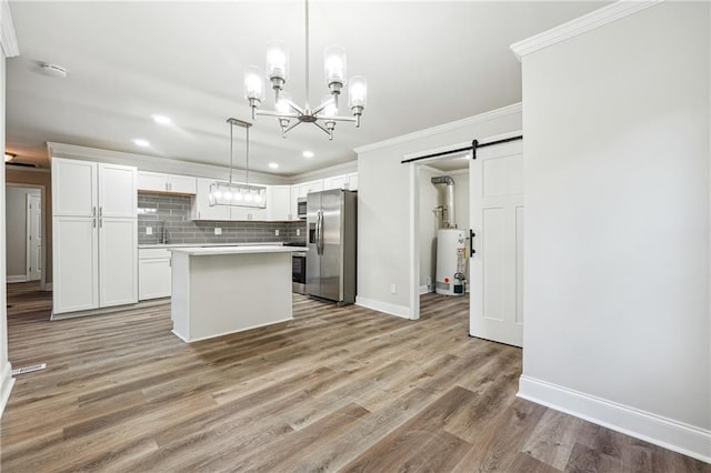 kitchen with wood-type flooring, a center island, white cabinets, a barn door, and appliances with stainless steel finishes