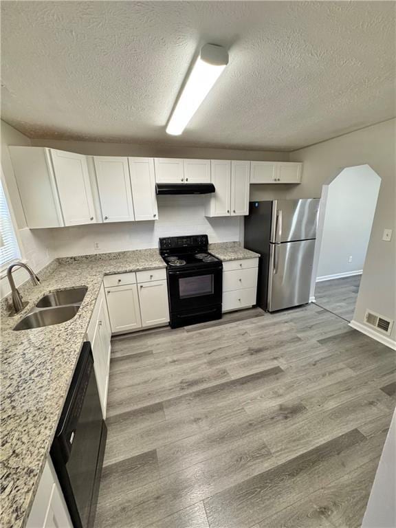 kitchen featuring white cabinets, light wood-style flooring, under cabinet range hood, black appliances, and a sink