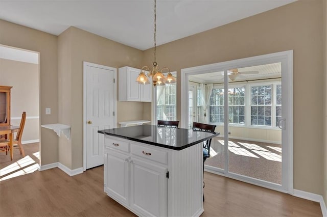 kitchen featuring dark countertops, pendant lighting, white cabinets, and light wood finished floors