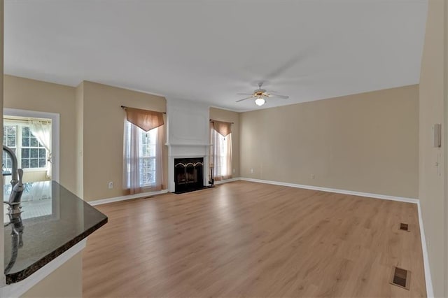 unfurnished living room featuring light wood-style floors, a healthy amount of sunlight, and a fireplace