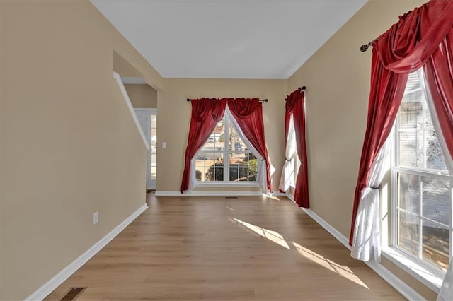 empty room featuring wood finished floors, visible vents, and baseboards