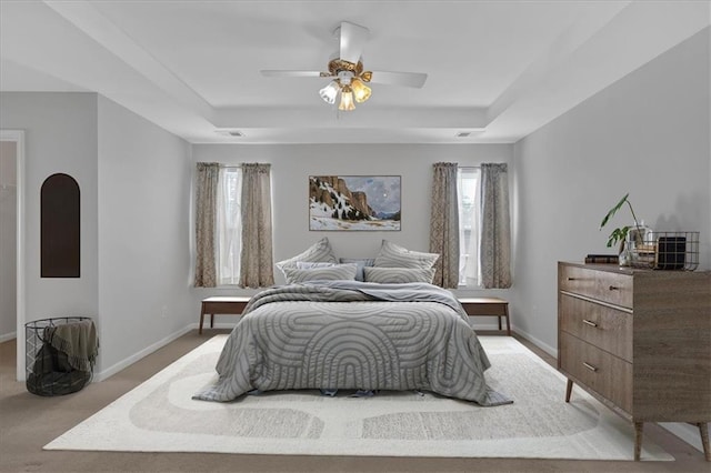 bedroom featuring a raised ceiling, visible vents, light carpet, and baseboards