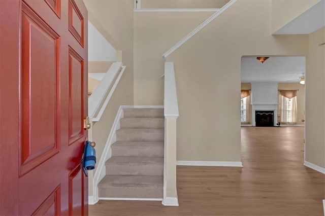 entrance foyer featuring stairs, a fireplace, baseboards, and wood finished floors