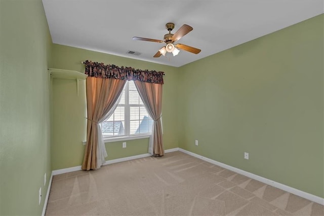 spare room featuring baseboards, visible vents, ceiling fan, and light colored carpet