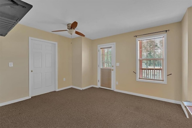 interior space with dark colored carpet, a ceiling fan, and baseboards