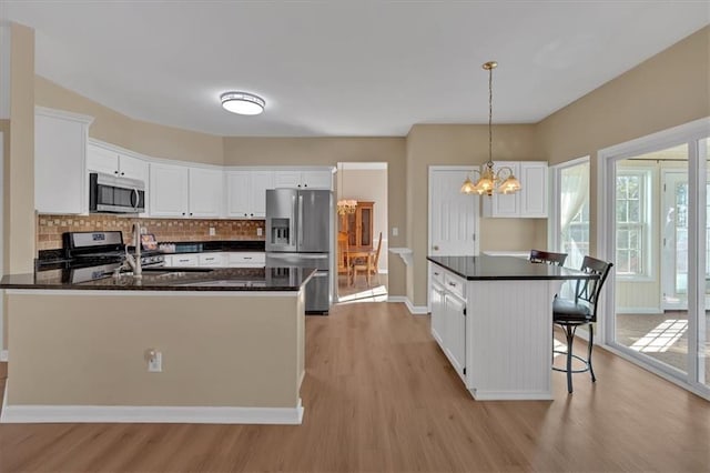 kitchen featuring appliances with stainless steel finishes, a wealth of natural light, white cabinets, and backsplash