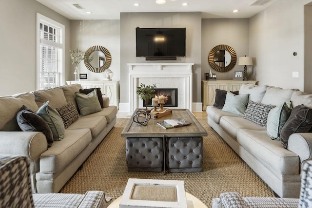 living area featuring visible vents, recessed lighting, a warm lit fireplace, and baseboards