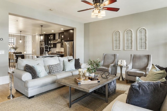 living area with baseboards, light wood-type flooring, and a ceiling fan