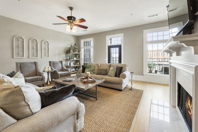 living room with plenty of natural light, a tile fireplace, visible vents, and ceiling fan