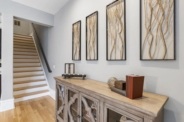 hallway featuring stairway, visible vents, and light wood-style floors