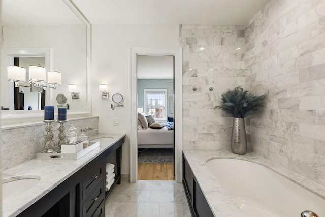 full bathroom with double vanity, a bathing tub, ensuite bathroom, and a sink