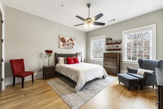 bedroom with a ceiling fan, visible vents, baseboards, and light wood-type flooring