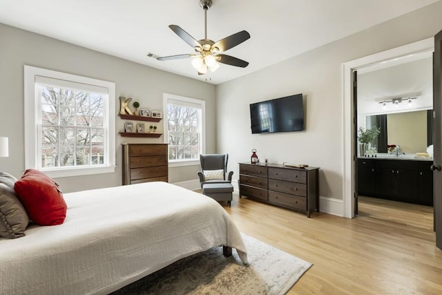 bedroom featuring visible vents, ensuite bathroom, light wood finished floors, baseboards, and ceiling fan