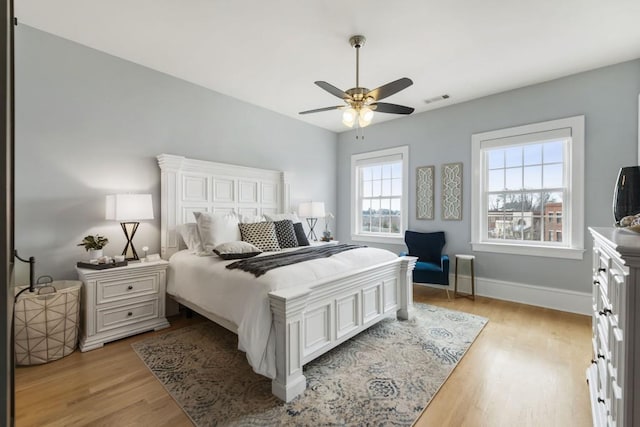 bedroom with ceiling fan, visible vents, light wood-type flooring, and baseboards