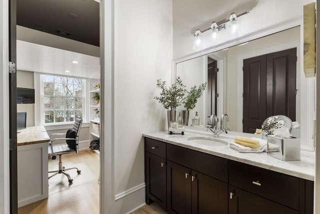 bathroom featuring recessed lighting, vanity, baseboards, and wood finished floors