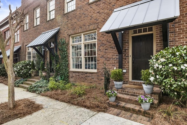 doorway to property featuring metal roof, brick siding, and a standing seam roof