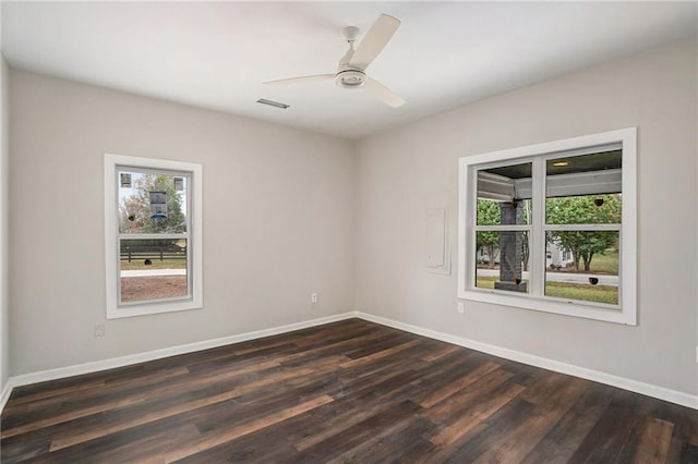 spare room featuring a healthy amount of sunlight, baseboards, and dark wood-style flooring