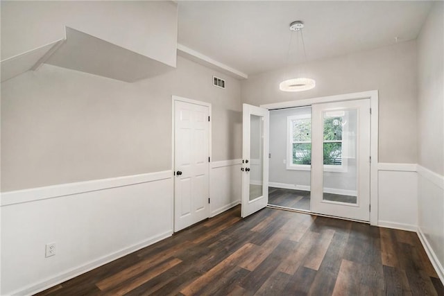 doorway with a wainscoted wall, wood finished floors, and visible vents