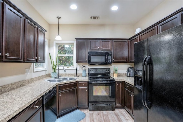 kitchen with black appliances, light wood-type flooring, dark brown cabinetry, pendant lighting, and sink