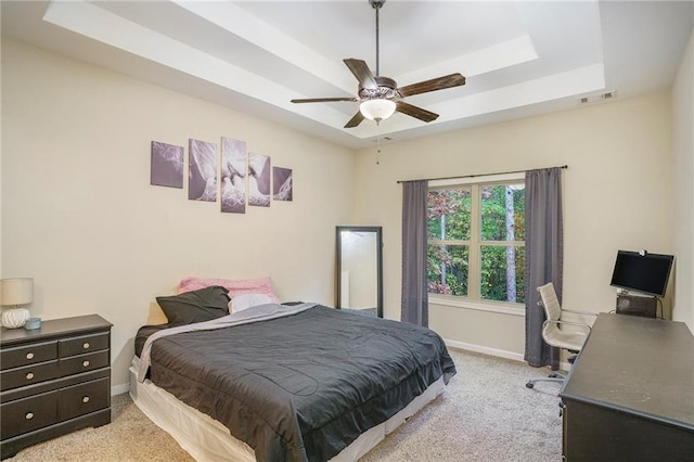 carpeted bedroom featuring ceiling fan and a raised ceiling