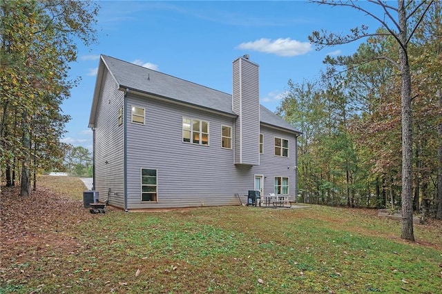 rear view of property featuring central AC and a lawn